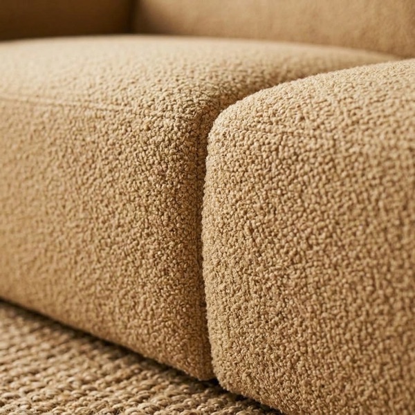 Close-up of the tan boucle sofa, where the seat cushion meets the arm